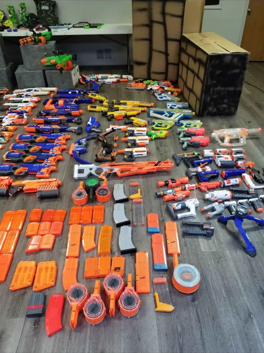 Close view of blasters, magazines and ammo drums laid out on the floor